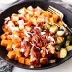 Sheet pan BBQ chicken, sweet potatoes, brussels sprouts and apples are in a bowl and ready to be eaten.