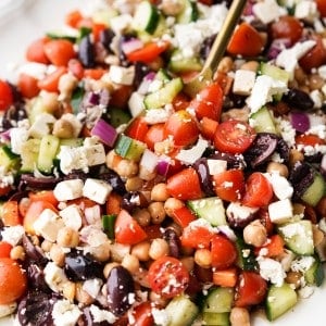 A close up picture of a spoon scooping up a salad with chickpeas.