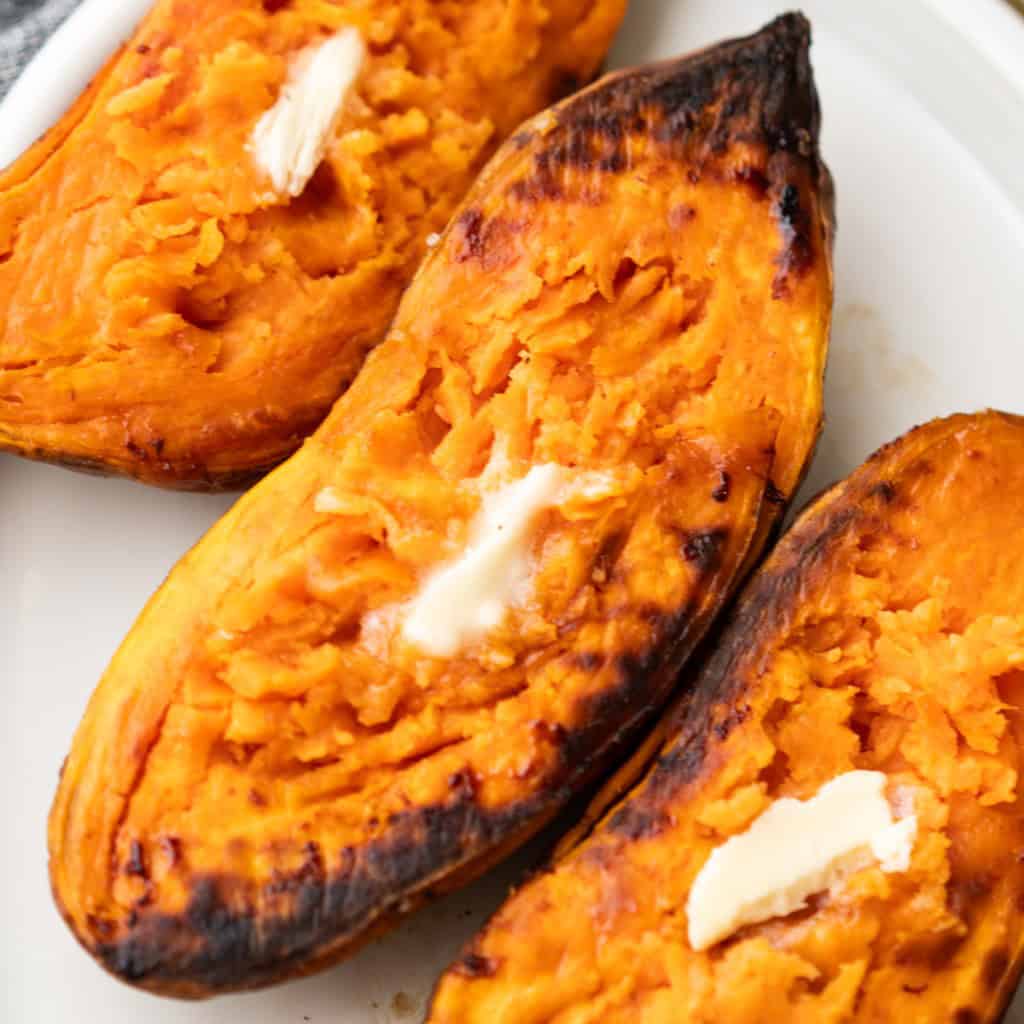 Caramelized sweet potato halves are dolloped with butter and ready to eat.