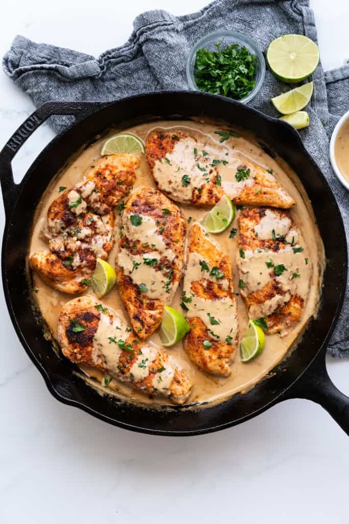Top down view of a skillet filled with six chicken breasts smothered in a creamy coconut sauce
