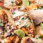 Close up picture of skillet coconut chicken garnished with lime wedges and parsley.