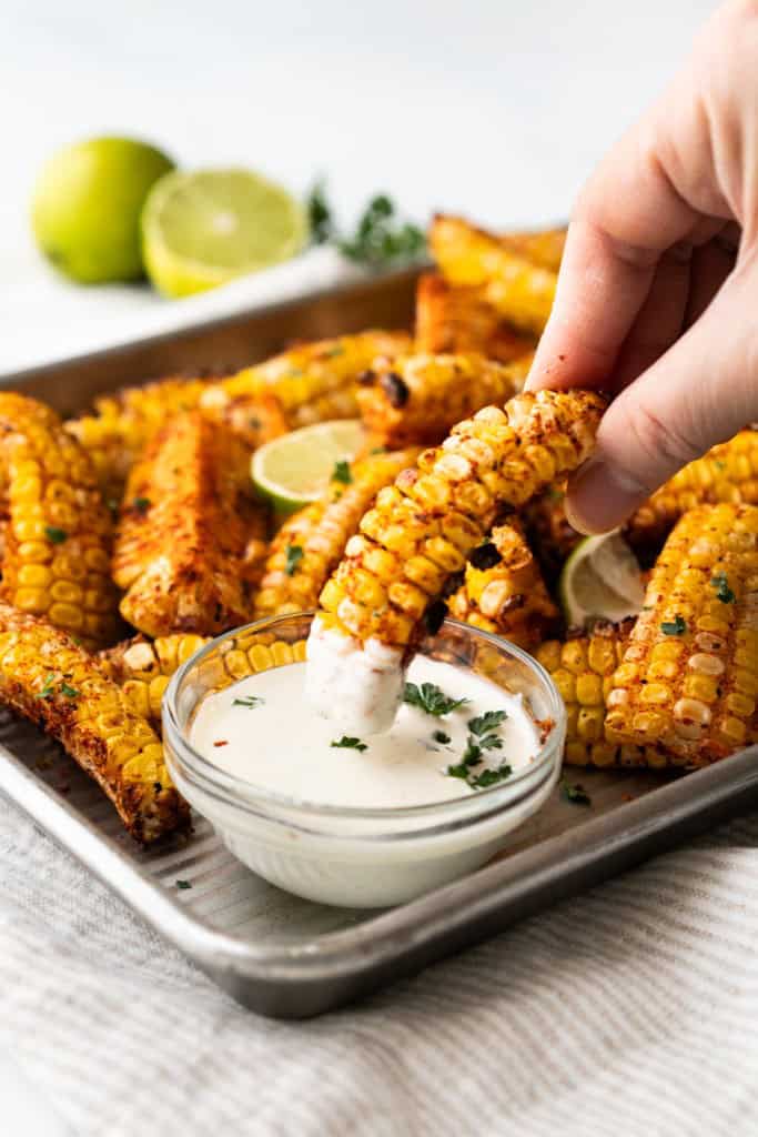 Corn rib is being dipped into a creamy sauce.
