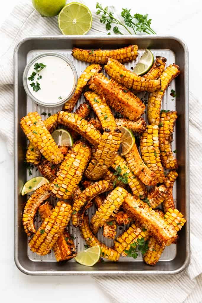 A small tray is filled with perfectly cooked corn ribs.