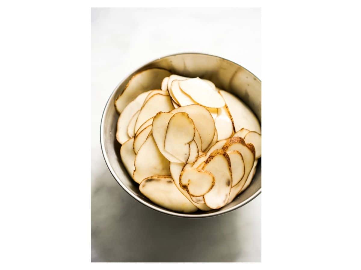 sliced, raw potatoes in a metal bowl