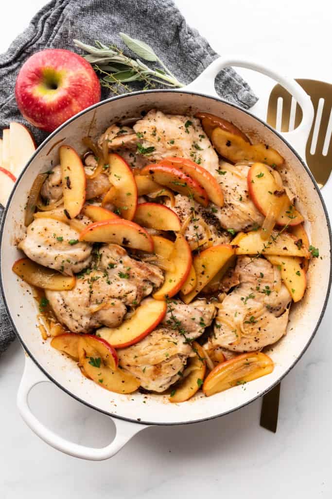 Freshly cooked apples sit on top of Apple Cider chicken thighs.