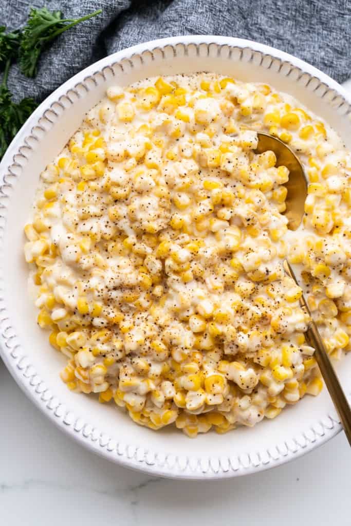 A shallow bowl is filled with slow cooker creamed corn.