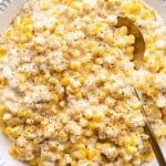 A spoon is resting in a bowl of crockpot creamed corn.
