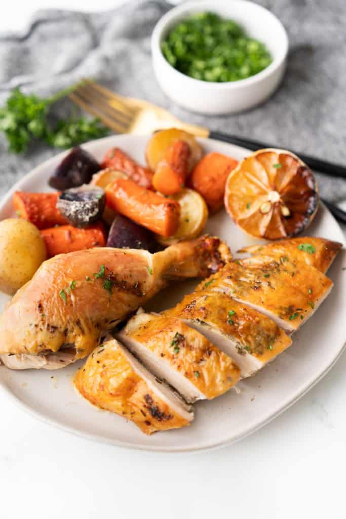 Carved roasted chicken and veggies have been plated and ready to eat.
