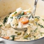 A ladle full of Creamy Chicken Gnocchi Soup is being lifted out of a Dutch oven.