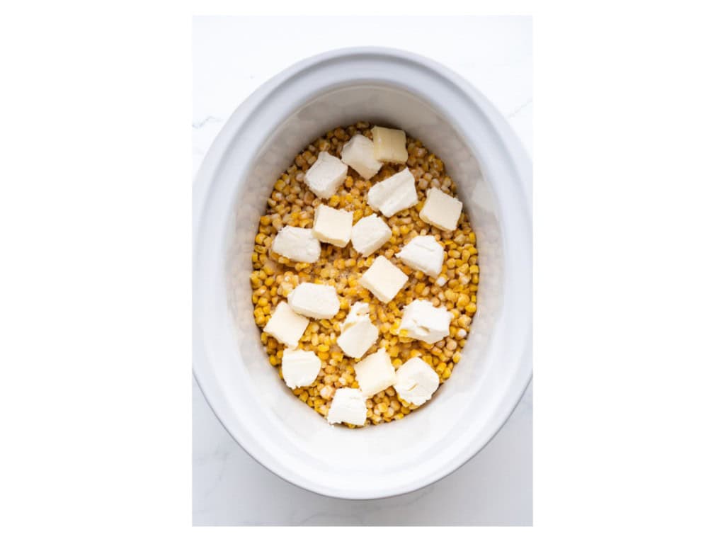 Creamed corn ingredients are added to a slow cooker.